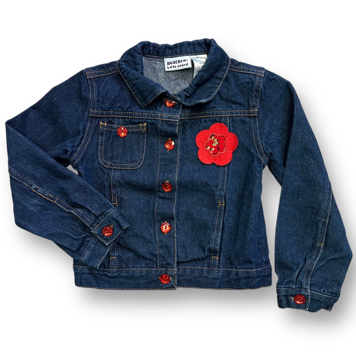 A girls' denim jacket with long sleeves, featuring a floral accent on the front, in a blue and red color scheme.