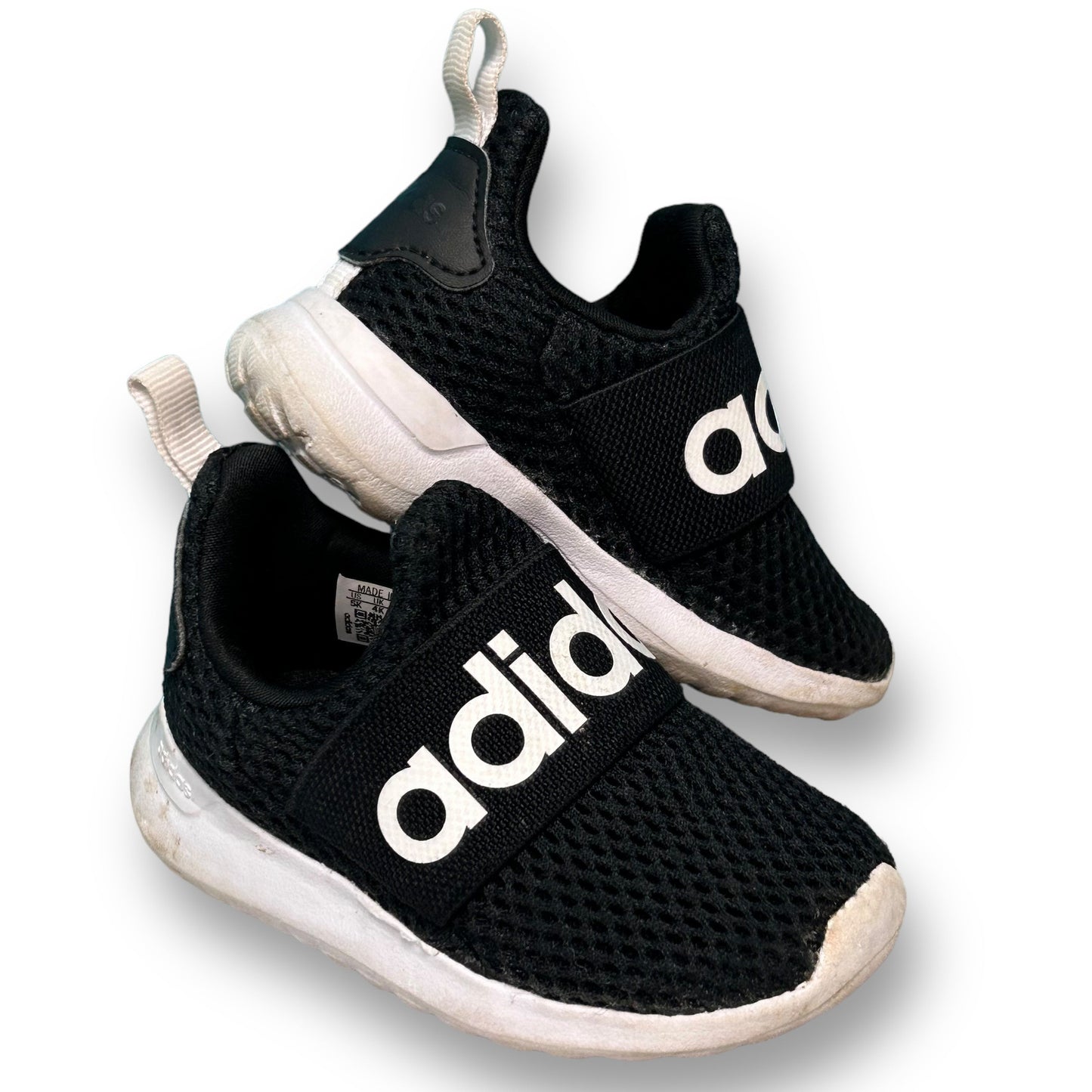 A pair of black Adidas slide-on athletic sneakers for toddlers with white branding on the side.