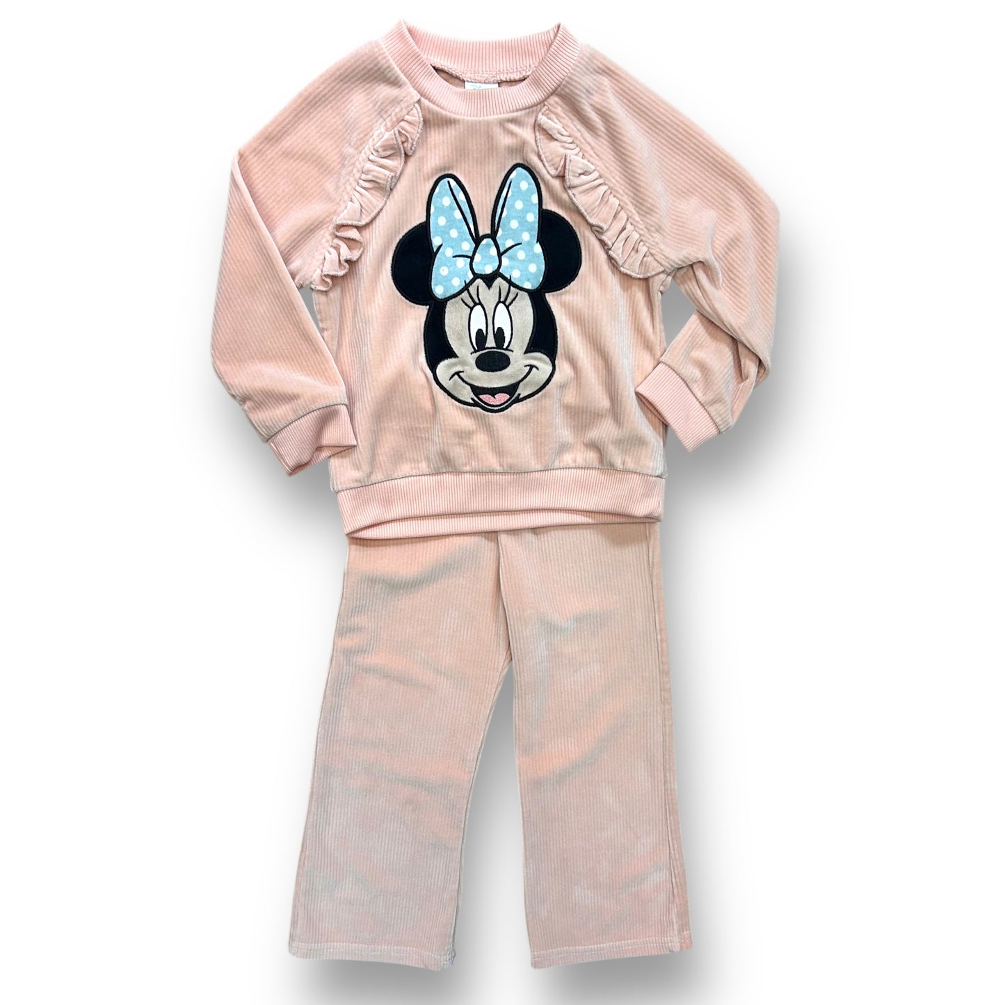 A peach-colored, ribbed velour bodysuit with a Minnie Mouse design on the front, complete with a bow detail, and matching pants with a ruffled edge.