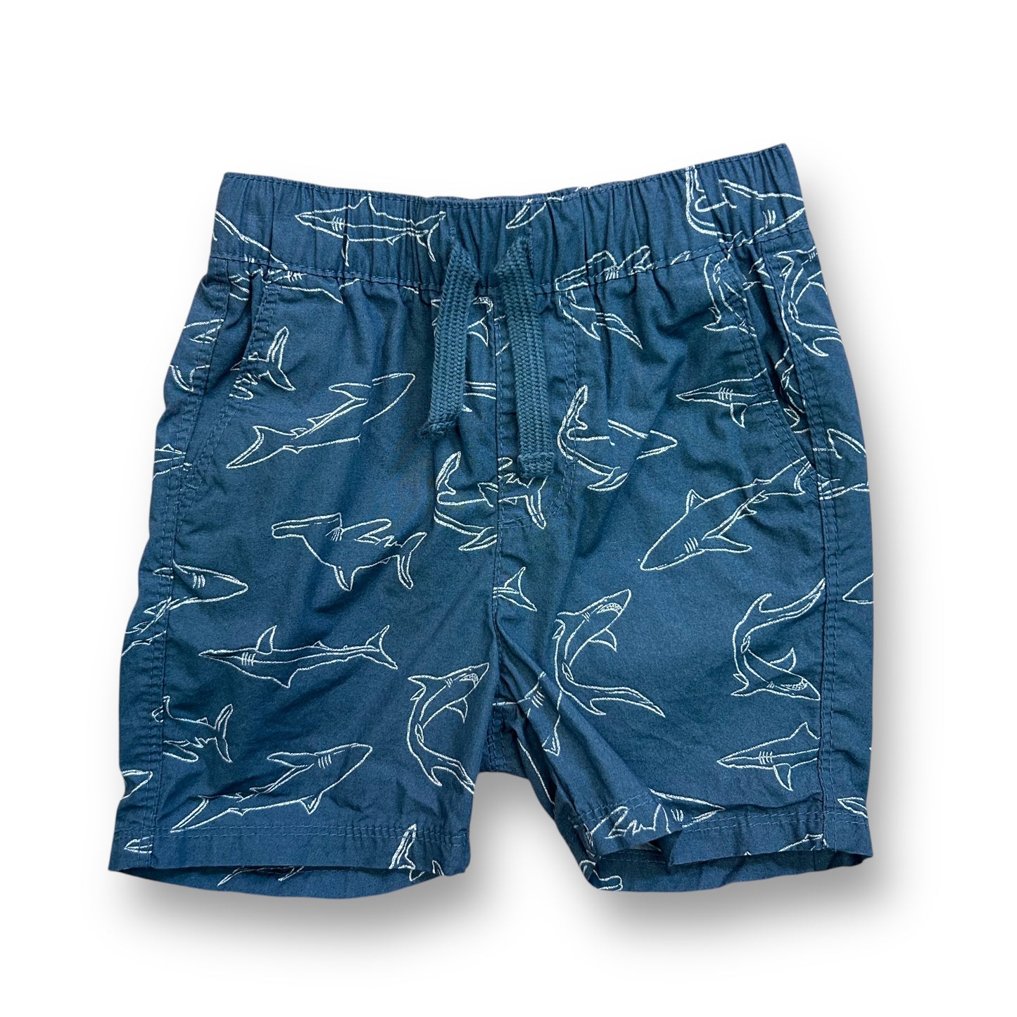 A pair of blue shorts with a shark print, designed for toddlers.