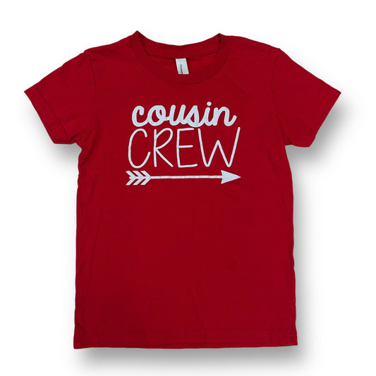 A red short sleeve shirt for boys with the text 'COUSIN CREW' printed in white on the front.