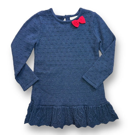 A dark blue shimmery sweater dress with a flowered pattern and a red bow detail on the shoulder.