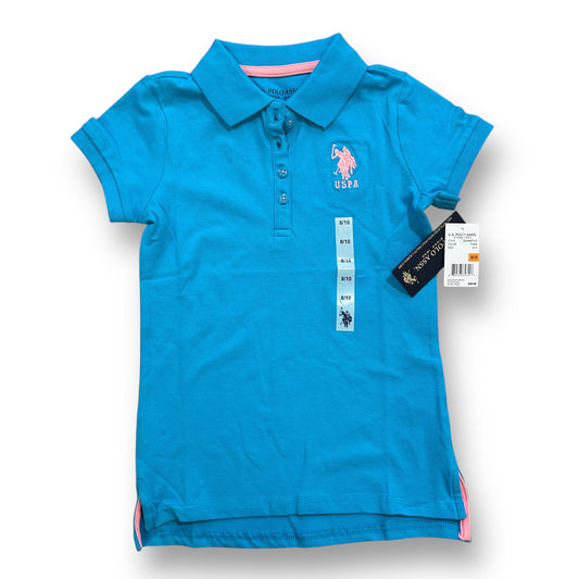 A teal blue girls' polo shirt with short sleeves, featuring a pink collar and pink embroidered logo on the chest, and a visible product tag.