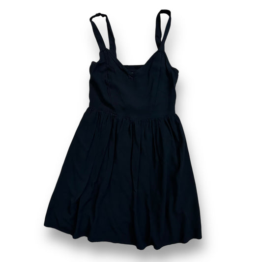 A black sleeveless knee-length dress with empire waist and thin straps.