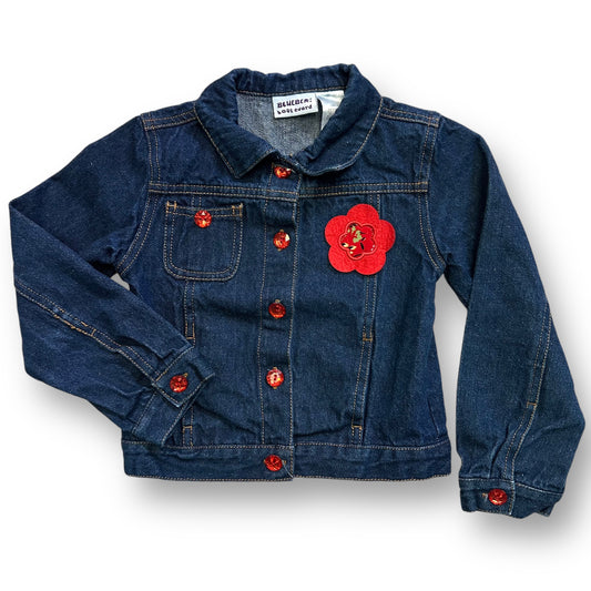 A girls' denim jacket with long sleeves, featuring a floral accent on the front, in a blue and red color scheme.