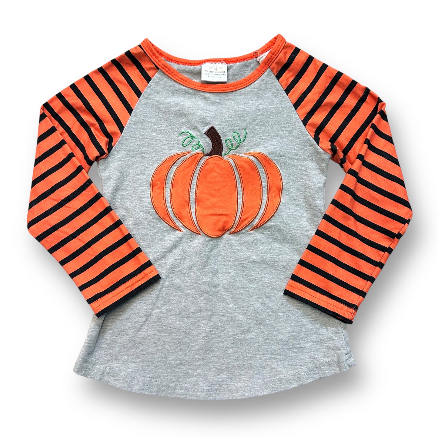 A long sleeve fall top for girls with stitched pumpkin and striped pattern on gray background.