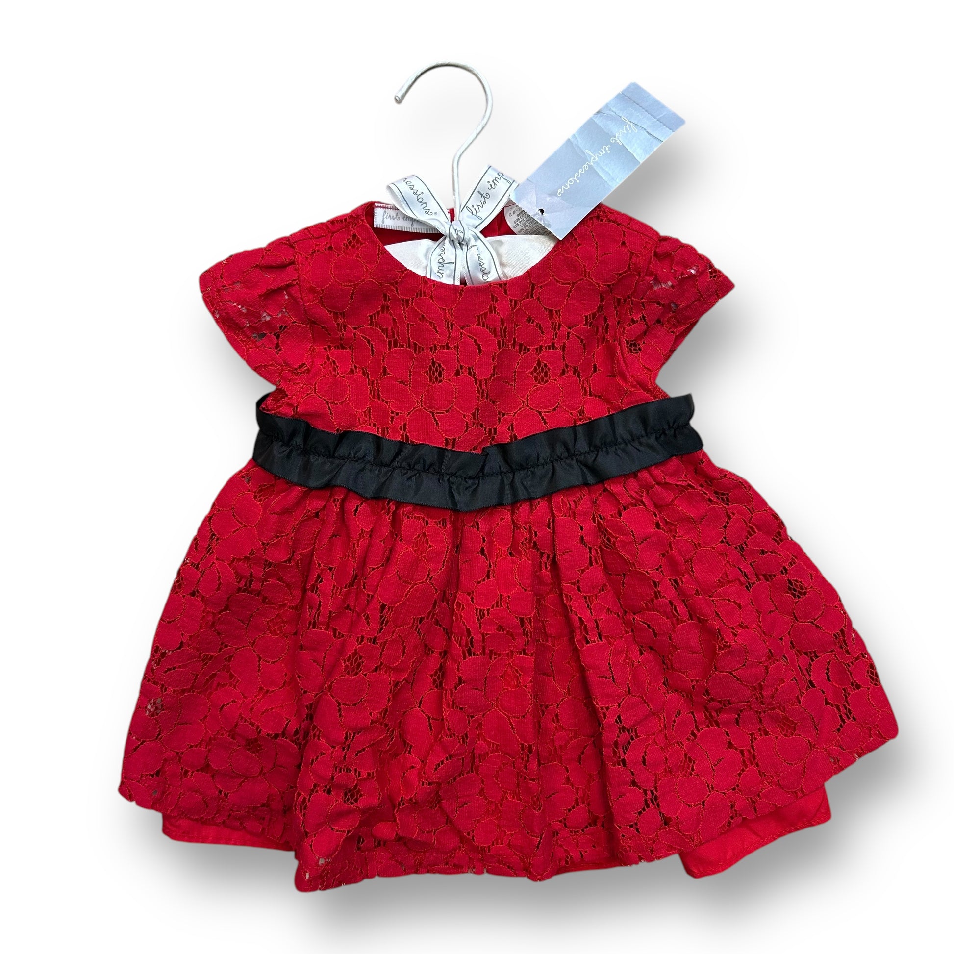 A red lace holiday dress for girls, with a solid pattern and a black belt, displayed on a hanger with a brand tag.