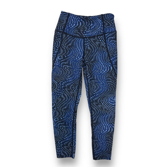 A pair of girls' athletic performance leggings in blue with a geometric pattern.