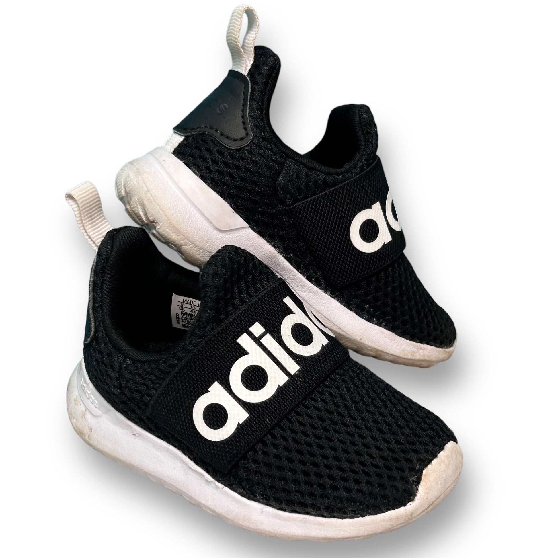 A pair of black Adidas slide-on athletic sneakers for toddlers with white branding on the side.