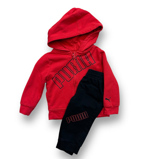 A boys' Puma hooded sweatsuit in black and red with the brand's logo, paired with black pants with the Puma logo on the leg.