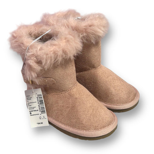 A pair of pink furry winter boots for toddler girls, with the brand tag visible on the bottom.