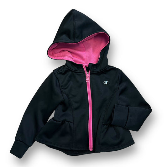 Girls black zippered hoodie with pink ruffle bottom and a logo on the chest.