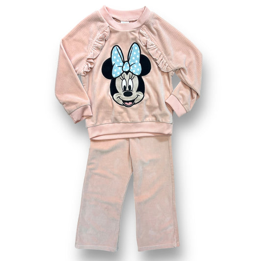 A peach-colored, ribbed velour bodysuit with a Minnie Mouse design on the front, complete with a bow detail, and matching pants with a ruffled edge.