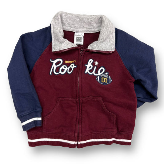 A maroon and navy zippered sweatshirt for boys with red and white accents and a logo on the front.