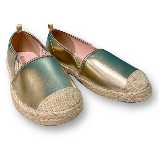 A pair of OshKosh youth girl size 3 gold slide-on casual shoes with a canvas upper and espadrille sole.
