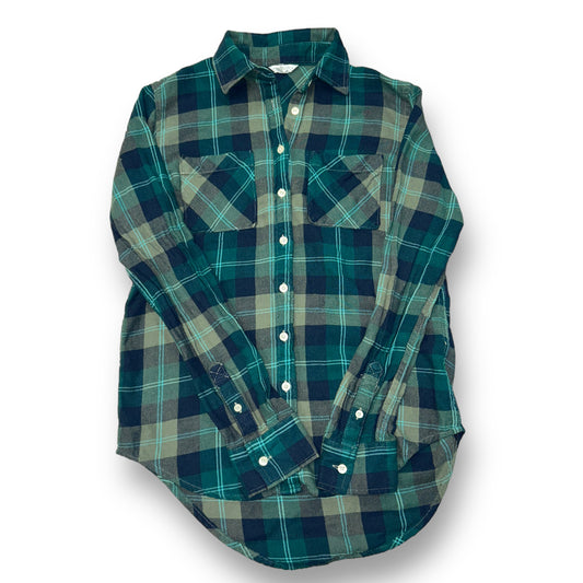 A long-sleeved, plaid button-down shirt in various shades of green, laid flat on a surface.