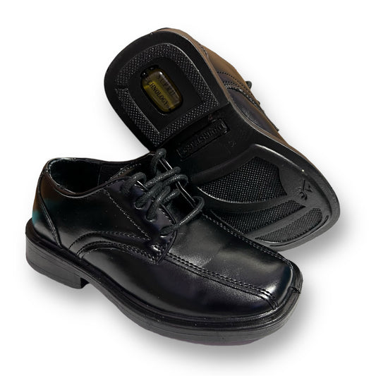 A pair of black casual dress shoes for toddlers with a lace-up closure and a rubber sole.