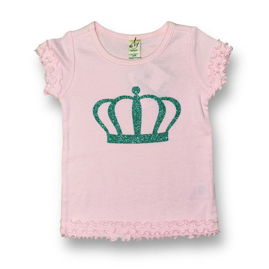 A light pink boutique top with princess ruffle sleeves and a green crown emblem on the front.